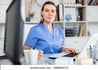 Young Woman Doctor Assistant Working In Medical Office Using Laptop Computer