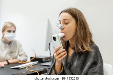Young woman with doctor during a spirography test, measuring breathing movements with spirometer at medical Spa salon