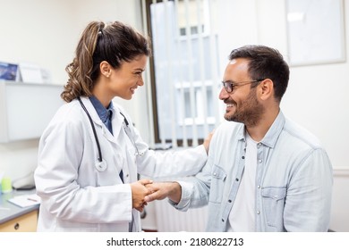 Young Woman Doctor Or GP In White Medical Uniform Consult Male Patient In Private Hospital. Female Therapist Speak Talk With Man Client On Consultation In Clinic.