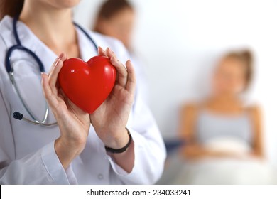 Young Woman Doctor Holding A Red Heart, Isolated On White