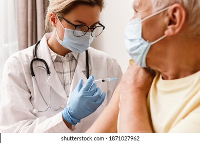 Young woman doctor injecting vaccine to elderly man during home visit - Powered by Shutterstock