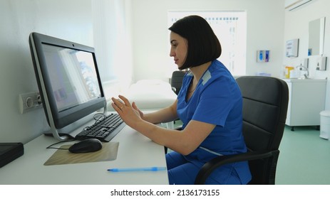 A young woman doctor sits at a table holding a mobile phone in her hands. Portrait of a woman doctor - Powered by Shutterstock