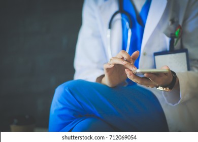 Young Woman Doctor Sitting With Your Phone. Woman Doctors.