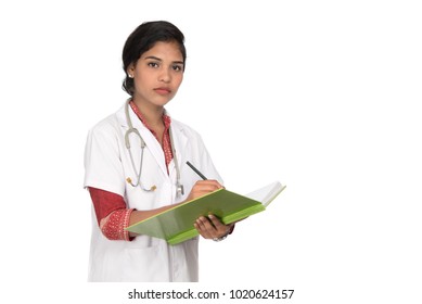 Young woman doctor with stethoscope is writing in book 