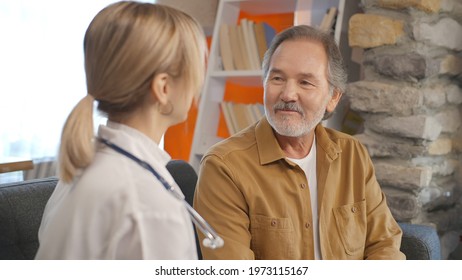 Young Woman Doctor Talking With Sick Old Man. Female Doctor Gives Informative And Motivating Speech To Her Patient. Old People Home Care Concept.