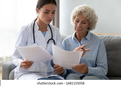 Young Woman Doctor Visit Senior Old Lady Patient At Home Explain Medical Documents Insurance, Attentive Female Give Consultation Close Sign Healthcare Agreement With Elderly Grandmother At Home