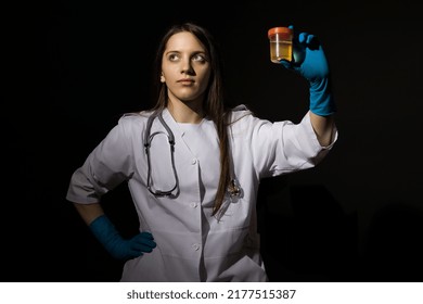 A Young Woman Doctor In A White Coat And Medical Gloves Holds A Jar With Urine Tests In Her Hand On A Black Background