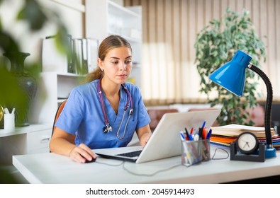 Young woman doctor is working at a computer, sitting at workplace in the resident's office in the medical clinic - Shutterstock ID 2045914493