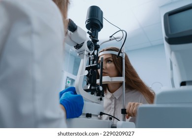 A young woman at a doctor's appointment. An optometrist examines the patient's vision using a slit lamp. - Powered by Shutterstock