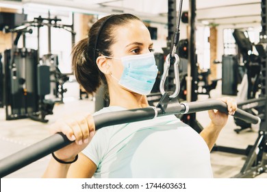 Young Woman Does Strength Exercises In A Gym With Her Mask On.