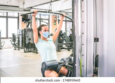 Young Woman Does Strength Training In A Gym With Her Mask On.