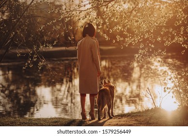young woman and dog enjoying the view by a river at sunset - Shutterstock ID 1579256449