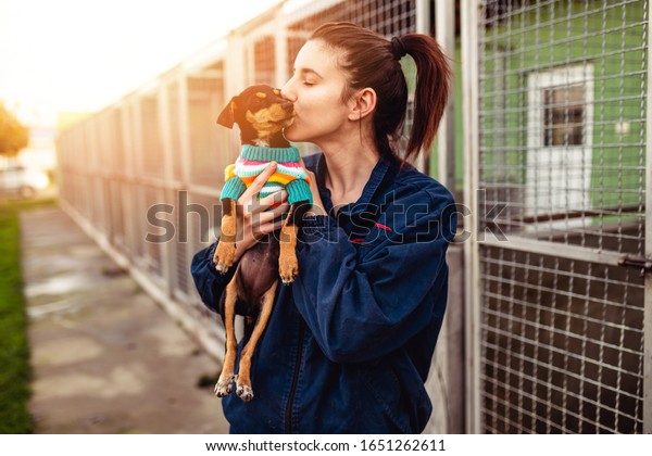 Young woman in dog\
shelter adopting a dog.