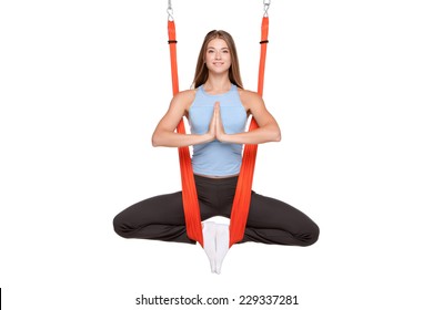 Young woman doing anti-gravity aerial yoga in hammock on a seamless white background.