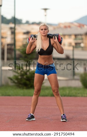 Young Woman Doing Bag Squat Exercise Outdoor