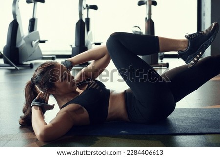 Young woman doing bicycle crunch exercise on exercise mat in gym.