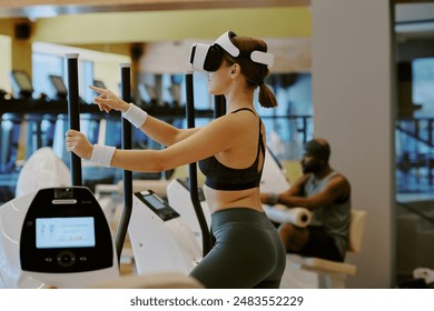 Young woman doing cardio on elliptical machine and playing VR game, while African American man doing leg superset on leg extension in background - Powered by Shutterstock