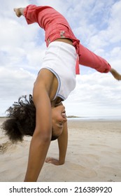 Young Woman Doing Cartwheel On Beach