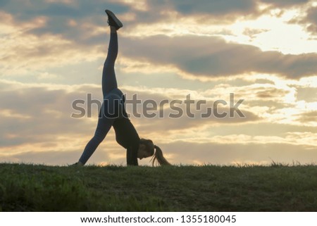 Young woman doing cartwheel on the grass Morning workout beautiful sunrise