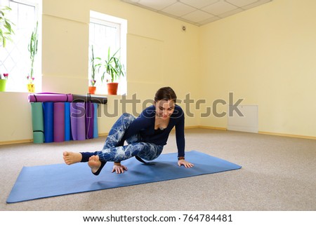 Young woman doing downward facing dog. Beautiful girl stretches back muscles. Concept of physical fitness, keep good physical form.