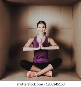 Young Woman Doing Exercises In Cardboard Box. Young Smiling Girl. Life In Little Cardboard Box. Uncomfortable Life. Personal Spase Concepts. Young Introvert. Sports And Healthy Lifestyle.