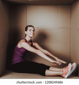 Young Woman Doing Exercises In Cardboard Box. Young Smiling Girl. Life In Little Cardboard Box. Uncomfortable Life. Personal Spase Concepts. Young Introvert. Sports And Healthy Lifestyle.