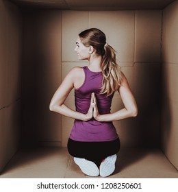 Young Woman Doing Exercises In Cardboard Box. Young Smiling Girl. Life In Little Cardboard Box. Uncomfortable Life. Personal Spase Concepts. Young Introvert. Sports And Healthy Lifestyle.