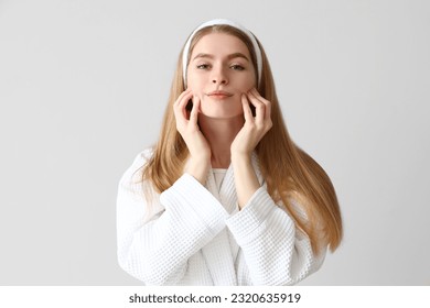 Young woman doing face building exercise on light background - Powered by Shutterstock