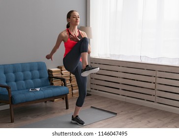 Young woman doing fitness training at home and walking high knees