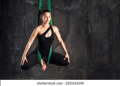 Young woman doing fly yoga stretching exercises in fitness training gym loft classroom. Sport and healthy lifestyle concept. Copy space.