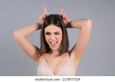 Young woman doing funny gesture with finger over head as bull horns. Crazy funny girl doing funny gesture with finger over head as bull horns.