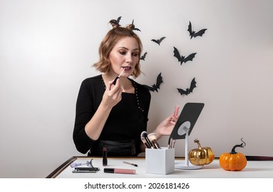 Young Woman Doing Halloween Makeup In Front Of The Mirror. Close Up Portrait. Halloween Makeup - Concept.