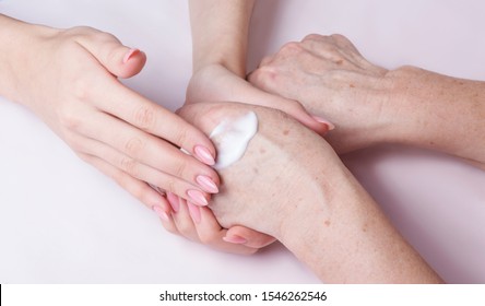 young woman doing hand massage with cream, courting older woman
