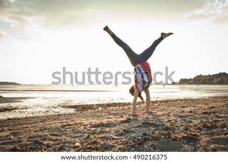 Young woman doing handstand on Bournemouth beach, Dorset, UK
