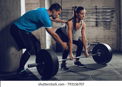 Young Woman Doing Hard Exercise At The Gym With A Coach.