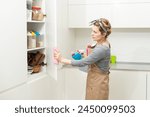 Young woman doing house chores. Woman holding cleaning tools. Woman wearing rubber protective yellow gloves, holding rag and spray bottle detergent. It