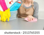 Young woman doing house chores. Woman holding cleaning tools. Woman wearing rubber protective yellow gloves, holding rag and spray bottle detergent. It