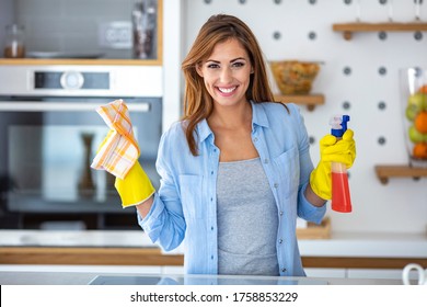 Young Woman Doing House Chores. Woman Holding Cleaning Tools. Woman Wearing Rubber Protective Yellow Gloves, Holding Rag And Spray Bottle Detergent. It's Never Too Late To Spring Clean