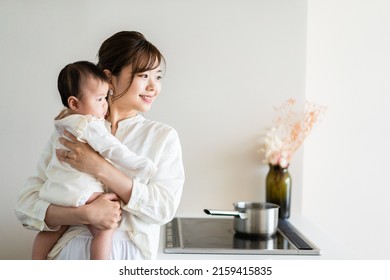 Young woman doing housework while carrying her baby - Powered by Shutterstock