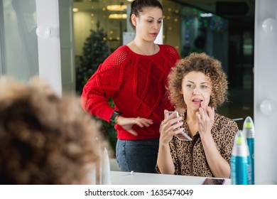 Young woman doing makeup in beauty salon in front of a mirror looking at her reflection - Shutterstock ID 1635474049