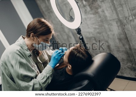 Young woman doing piercing at beauty studio salon
