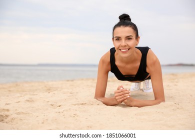 Young Woman Doing Plank Exercise On Beach, Space For Text. Body Training