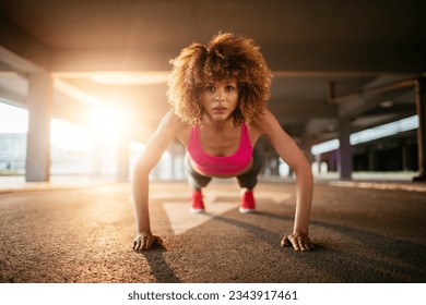 Young woman doing push ups and exercising in a parking lot - Powered by Shutterstock