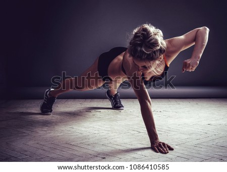 Young Woman Doing Push-Ups. Dark background