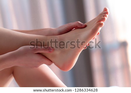 Young woman doing a relaxing foot massage at home on the bed after a long, hard working day. Manual therapy. Treatment pain, fatigue and discomfort legs
