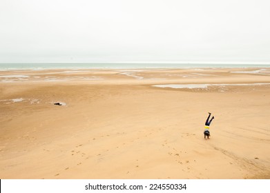 Young woman doing a somersault on a beach in autumn, during low tide - Powered by Shutterstock