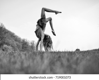 Young Woman Doing Somersault On Grass. Sport And Leisure, Freedom