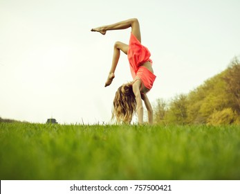 Young Woman Doing Somersault On Grass. Sport And Leisure, Freedom