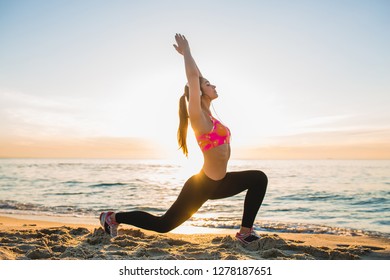 young woman doing sport exercises on sunrise beach in morning, stretching, healthy lifestyle, listening to music on headphones, yoga