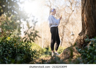 Young Woman Doing Sports And Listening To Music In The Park